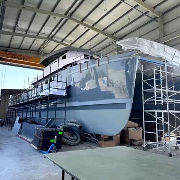 Large fiberglass hull under construction with scaffolding