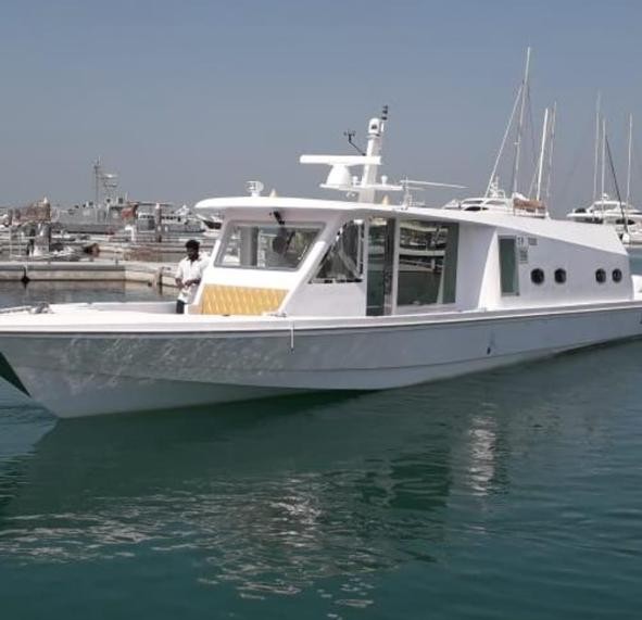 White fiberglass cabin cruiser passenger boat underway in a Gulf harbour