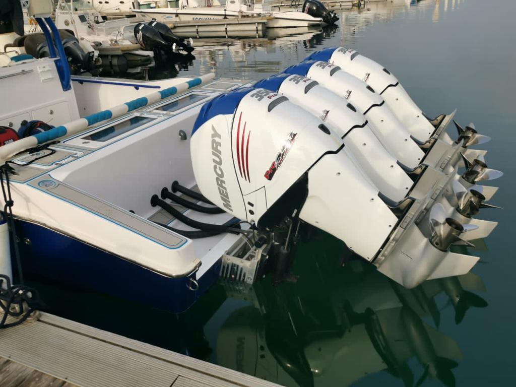 Close-up of four Mercury 350 Pro XS outboards tilted up over the water on a blue hull