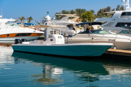 Teal center console patrol boat moored at marina among yachts
