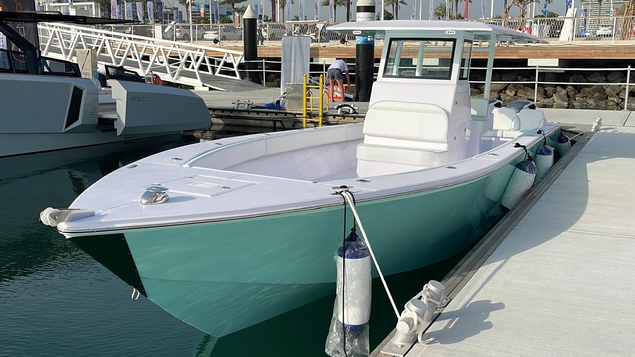 Mint and white center console boat fendered alongside a marina pontoon