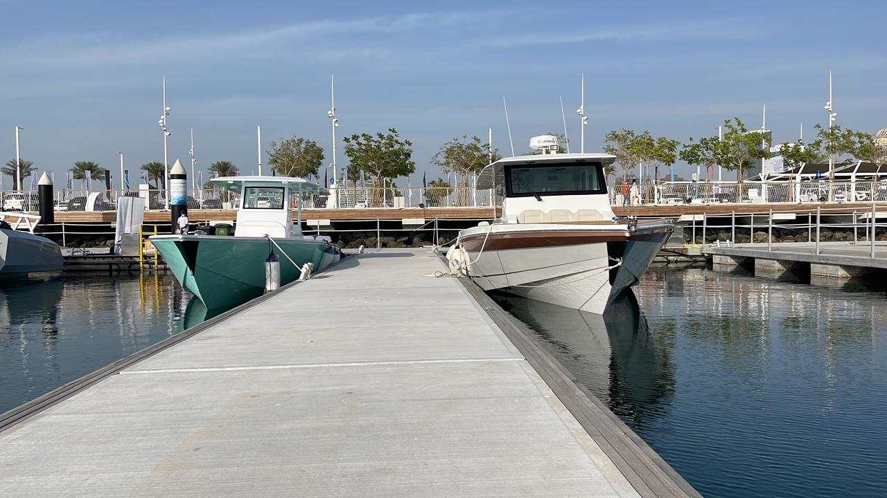 Two KHA Marine boats berthed bow-on either side of a marina pontoon under blue sky